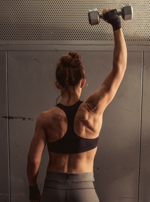 Woman lifting weights as part of a strength training routine for fat loss.